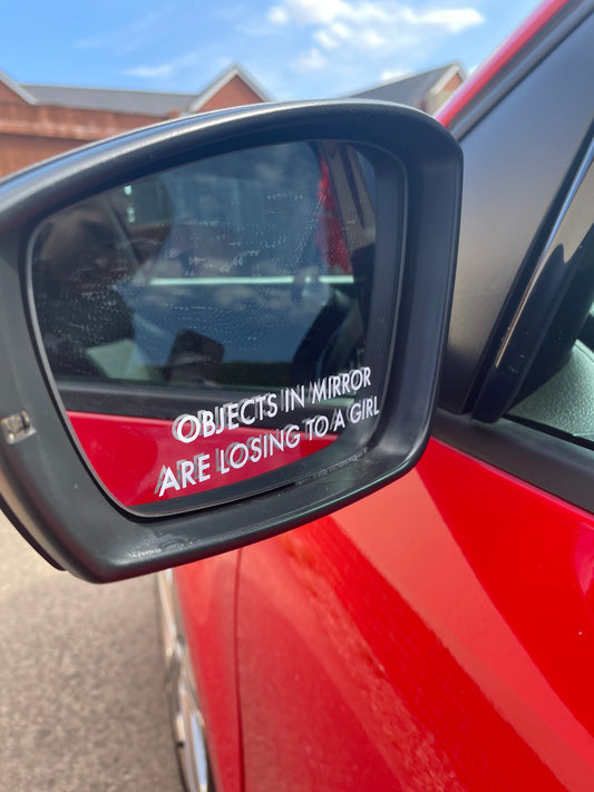 ‘Objects in mirror are losing to a girl’ sticker
